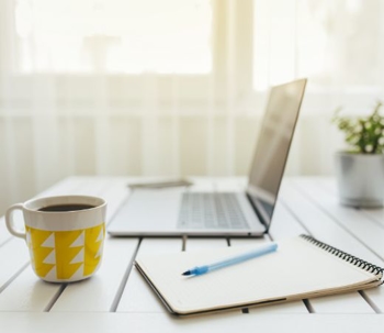 Image of a laptop and notepad on a desk